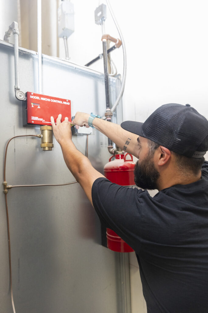 Technician servicing wall-mounted fire protection equipment