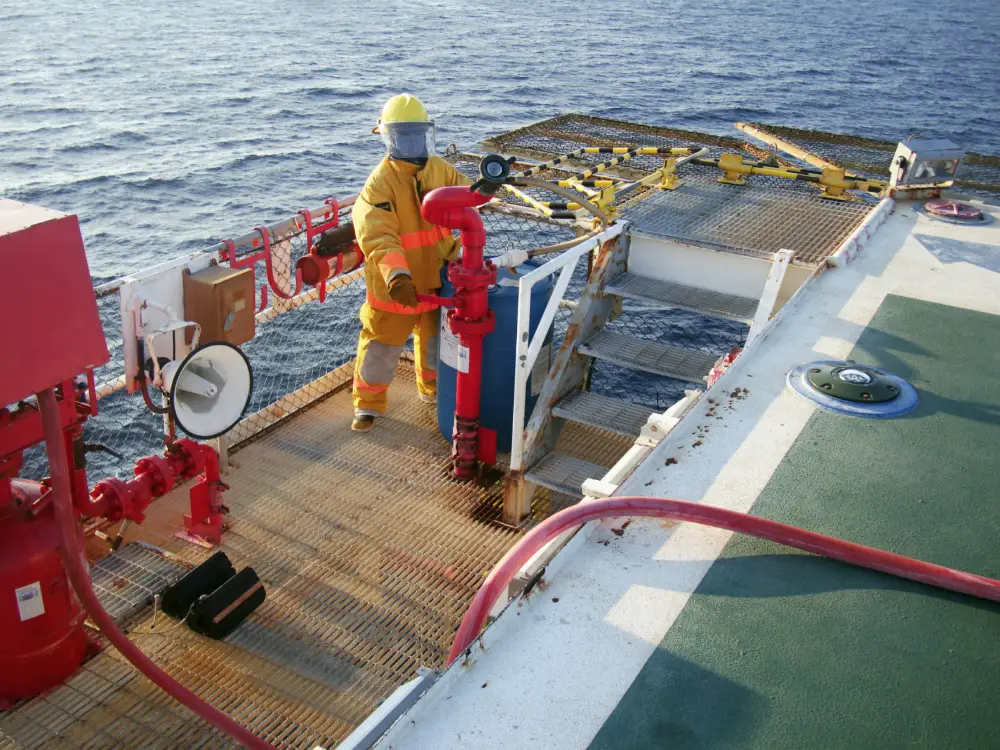 Crew member in safety gear on an offshore vessel deck with fire equipment