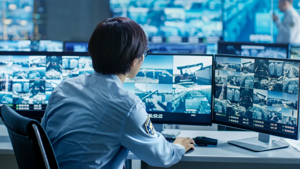 Security officer monitoring surveillance screens in a control room