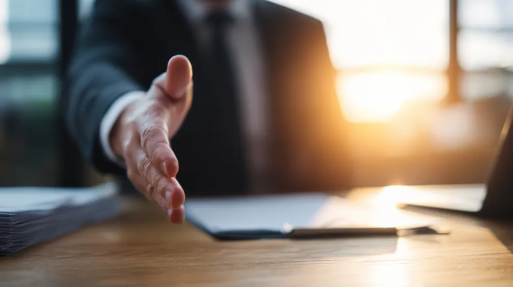 Businessperson extending a hand for a handshake across a desk