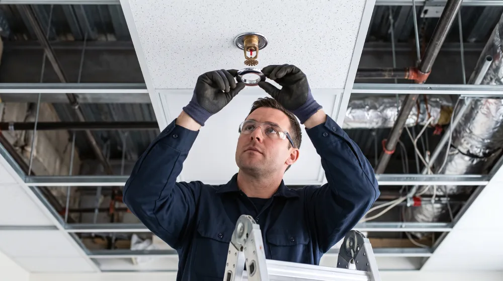 Technician installing a ceiling fire sprinkler head