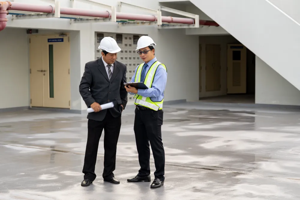 Two professionals in hard hats walking through an empty commercial building