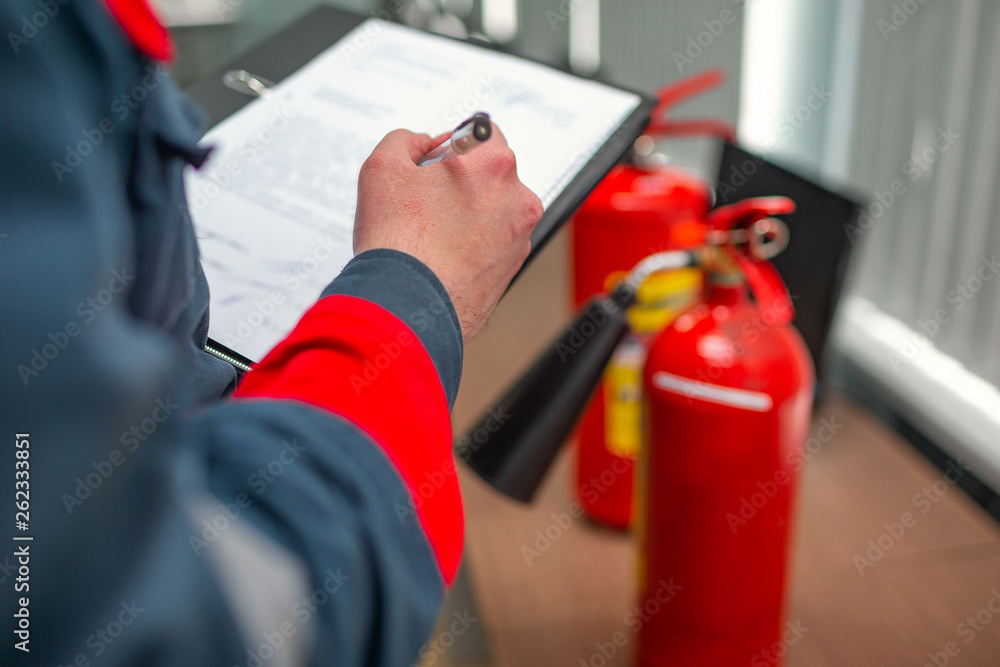 Inspector with a tablet checking fire extinguishers