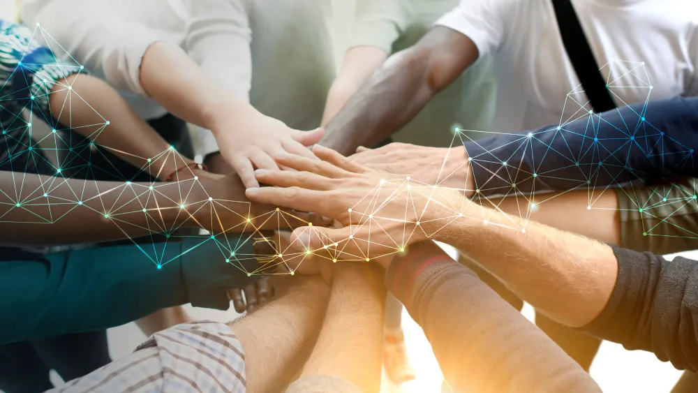 Team members stacking hands together in a show of unity