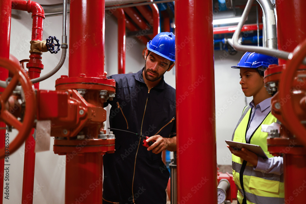 Technicians in hard hats inspecting red fire sprinkler piping
