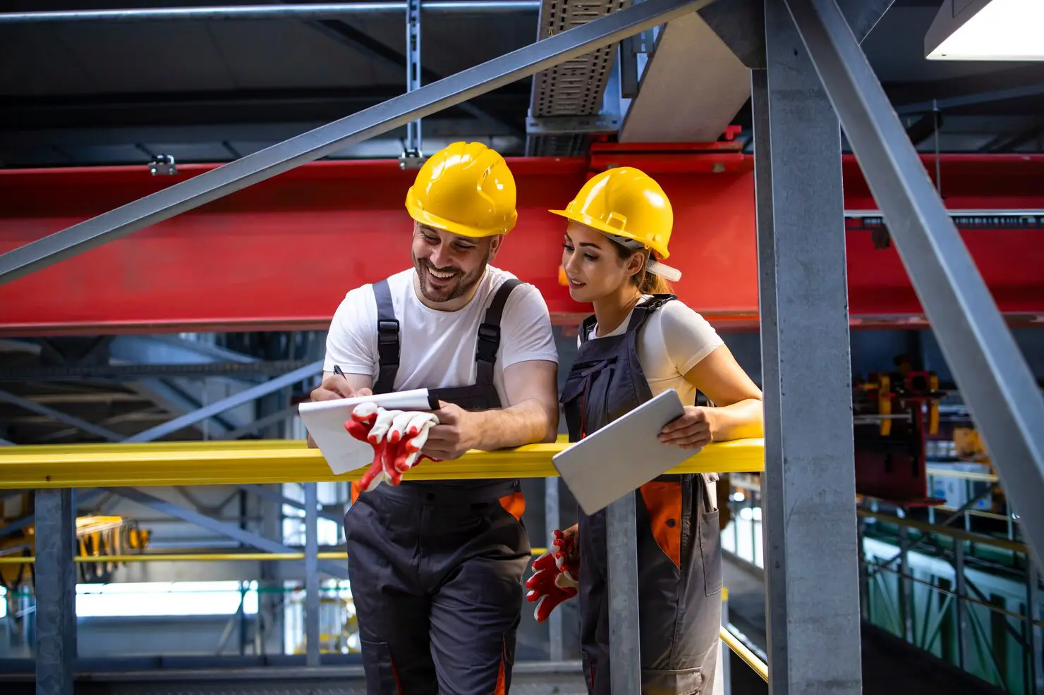 Two technicians in hard hats reviewing a clipboard in an industrial facility