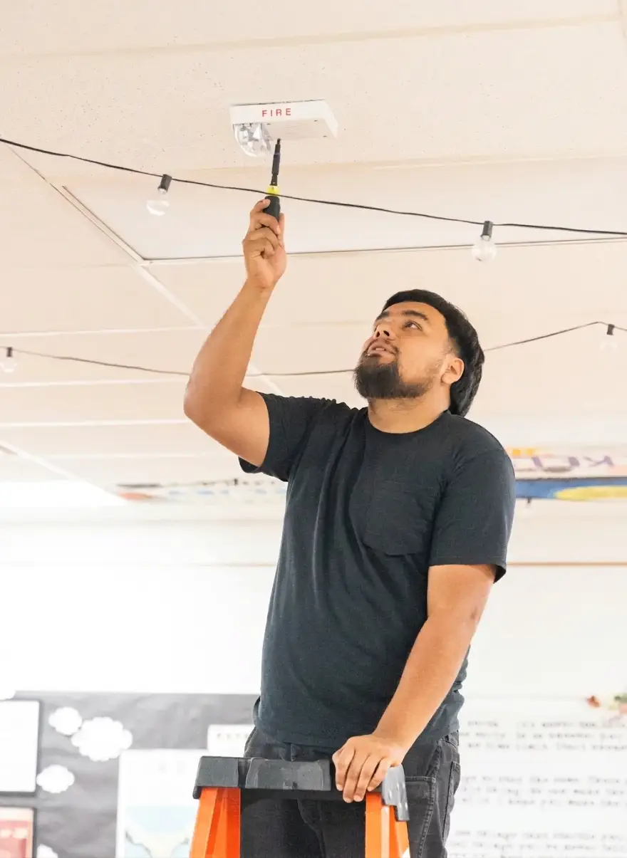 Technician installing a ceiling smoke detector
