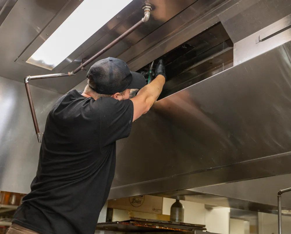 Technician inspecting a kitchen hood fire suppression system