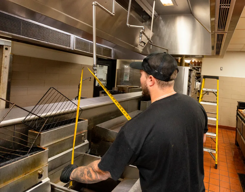 Technician inspecting a kitchen hood fire suppression system in a commercial kitchen
