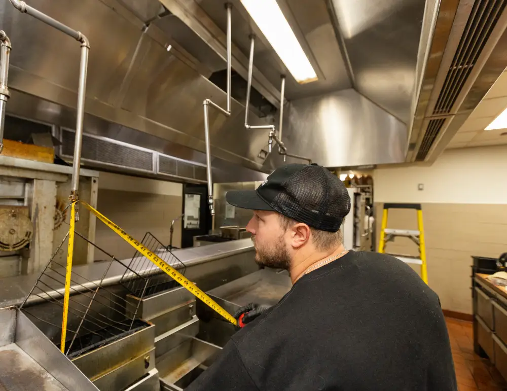 Technician inspecting a commercial kitchen fryer line