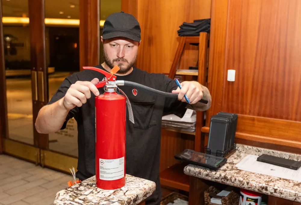 Technician inspecting a fire extinguisher in an office lobby